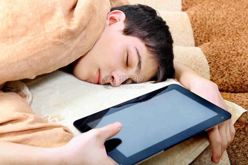使用平板电脑的青少年睡眠男性瞌睡倦怠药片枕头沙发被单说谎房间毯子图片