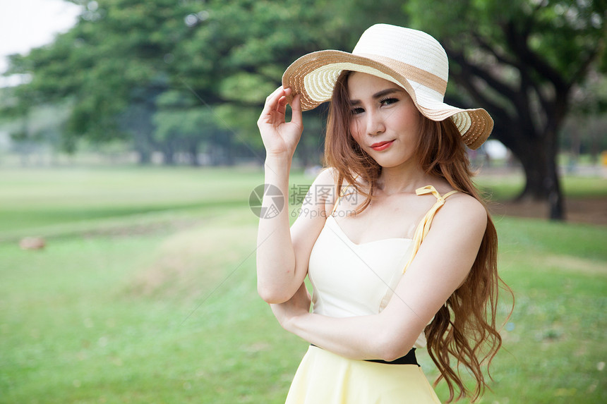 戴帽子的女人在公园里喜悦快乐女性叶子冒充阳光草地场地头发享受图片