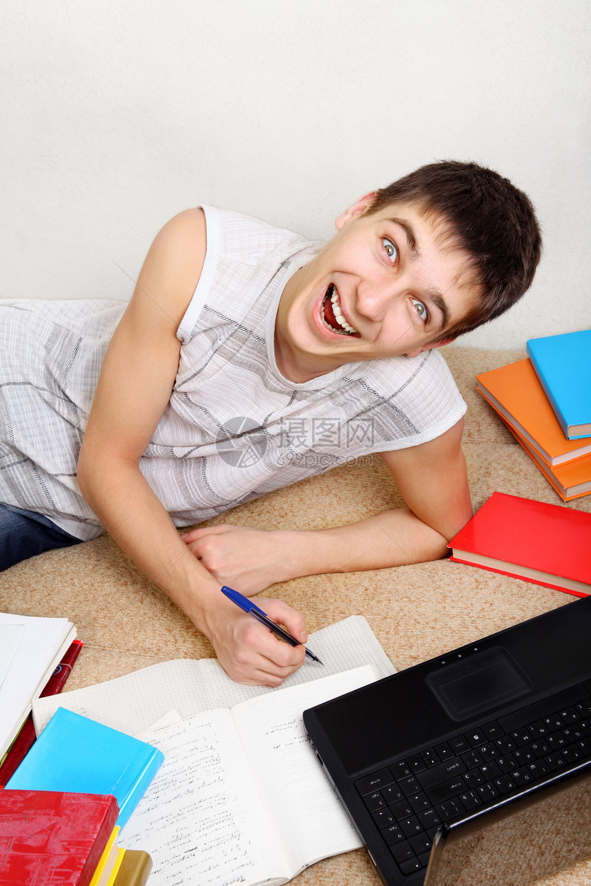 勤奋的青少年做家庭工作笔记本喜悦工具小伙子青年男性快乐微笑考试测试图片