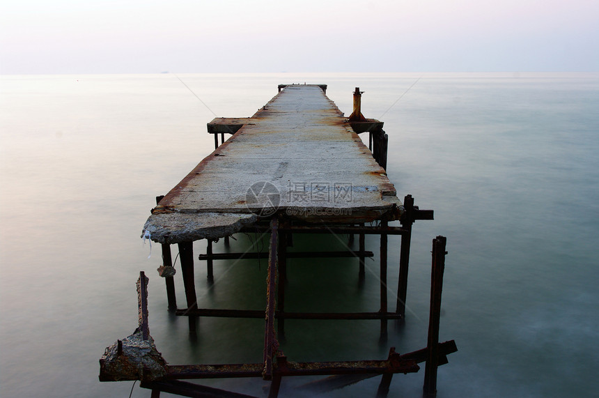 日出时弃置在海上的混凝土码头图片