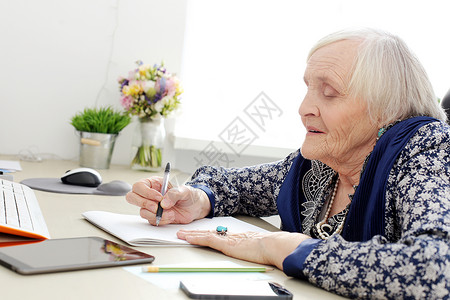长相快乐的老年妇女头发桌子奶奶杯子记事本女士知识皮肤学习房子背景图片