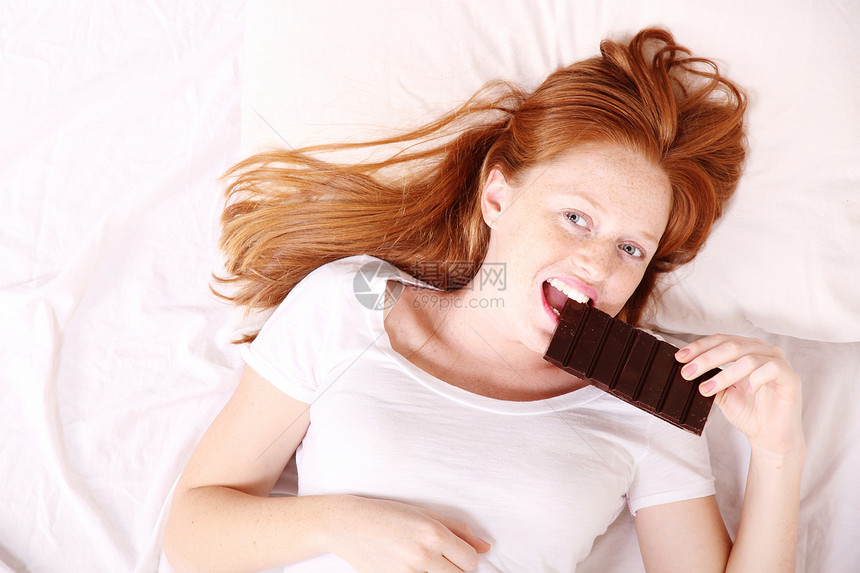 吃巧克力女孩享受枕头甜点糖果女士喜悦女性闲暇重量图片