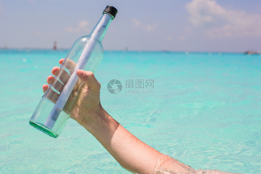 手背景蓝色天空中含有信息插件的瓶旅游土地文档玻璃海滩贝壳瓶子晴天海岸线热带图片