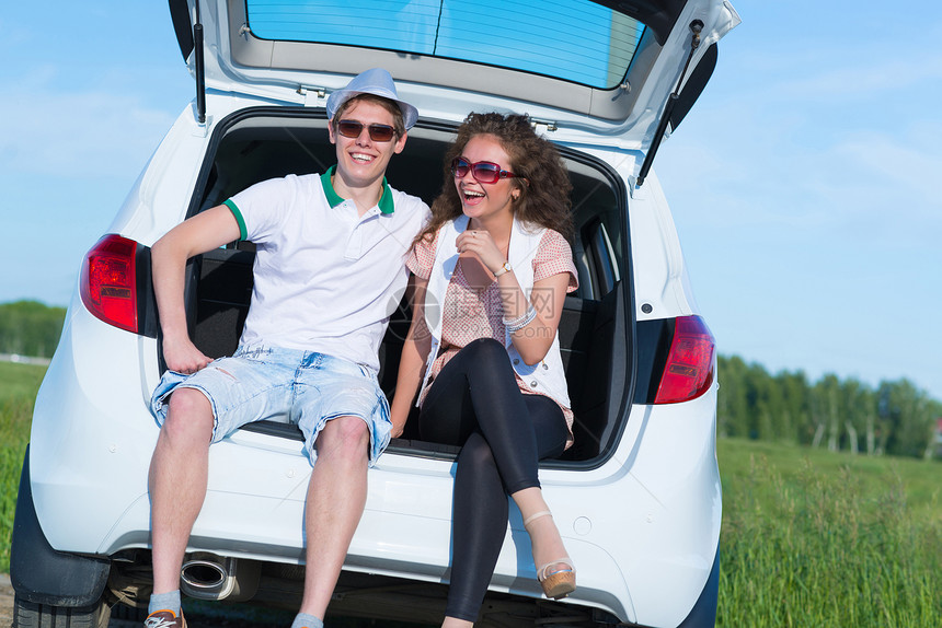 年轻夫妇坐在露天后备箱夫妻驾驶男人车辆汽车成人太阳镜运输女孩快乐图片