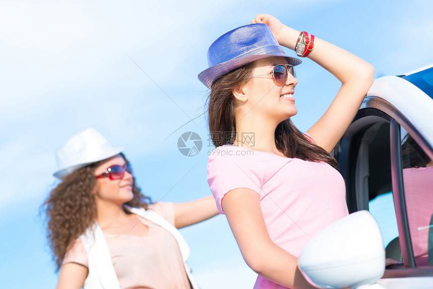 两名身戴墨镜的年轻美女孵化微笑男性女性日落成人帽子闲暇树干假期图片