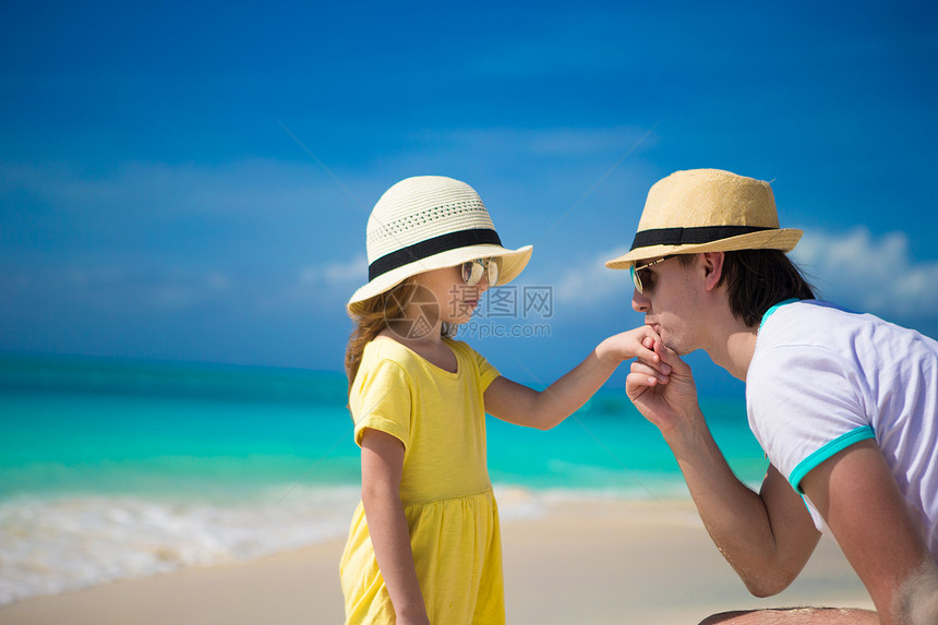 快乐的爸爸亲吻他女儿在海滩上的手热带成人家庭情调海岸婴儿海洋假期父母女孩图片