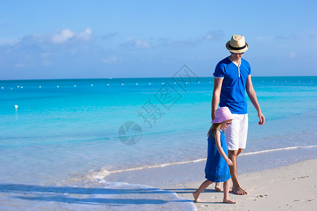 特克斯和凯科斯群岛可爱的小可爱女孩和她父亲在海边走着热带父母海岸线蓝色家庭海滩异国成人女儿乐趣背景