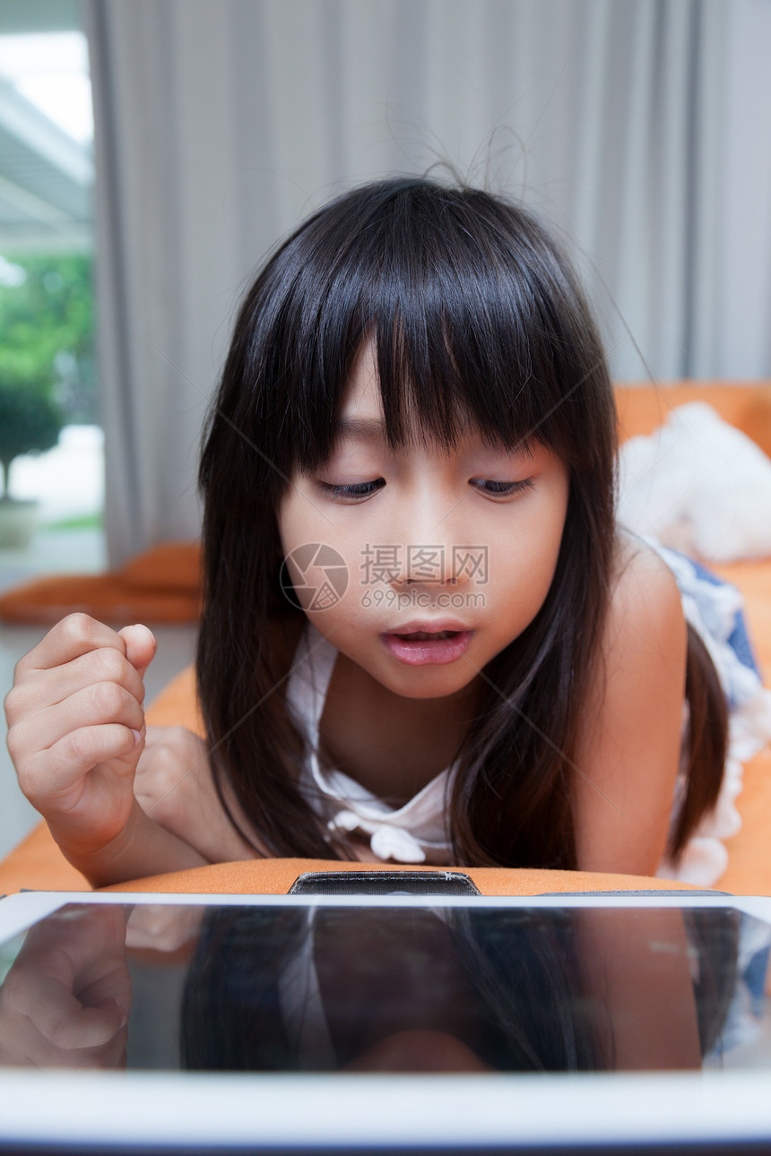 女孩玩平板电脑教育孩子乐趣互联网屏幕房子展示技术沙发女性图片