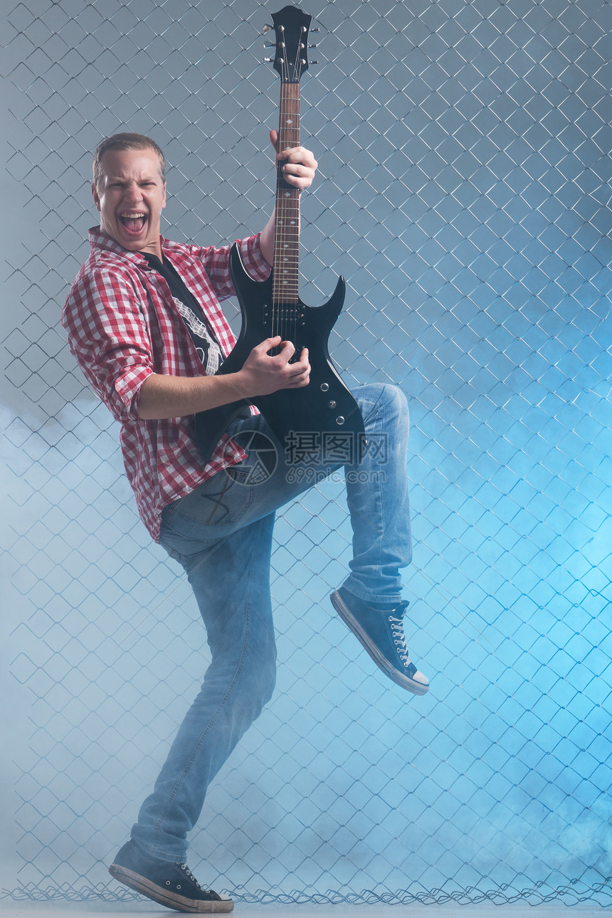 年轻音乐家 有一把吉他 在栅栏背景上流行音乐星星音乐金属吉他手快乐独奏乐器歌曲摇杆图片