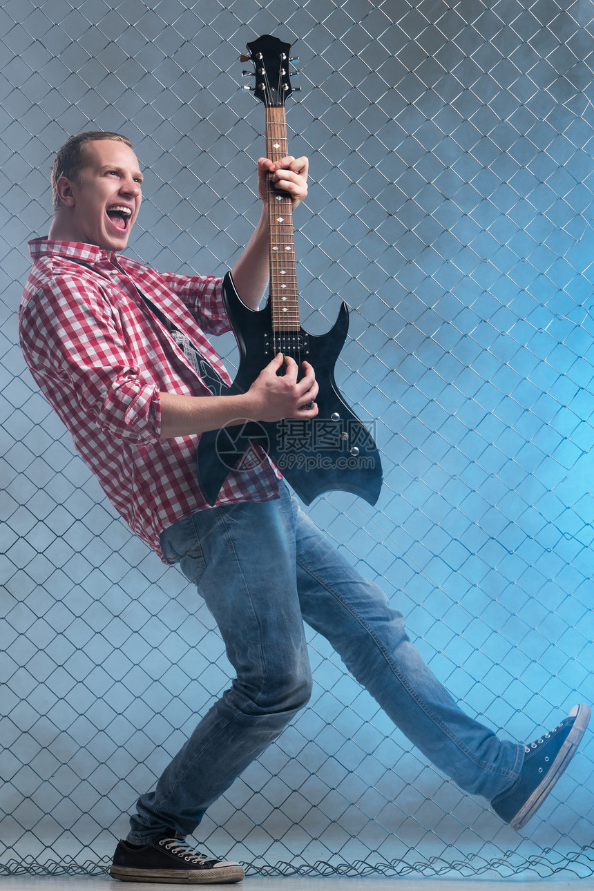 年轻音乐家 有一把吉他 在栅栏背景上玩家衣服金属歌曲衬衫流行音乐艺术家歌手男人尖叫图片