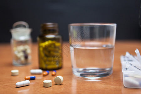 旧药瓶和几颗药丸放在木制桌子上药片日历副作用药店案件保险箱日程药物胶囊剂量背景图片