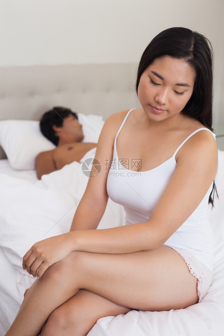 男朋友睡觉时坐在床上结束床边的女人快乐女性苏醒女士微笑闲暇被子住所公寓思维图片