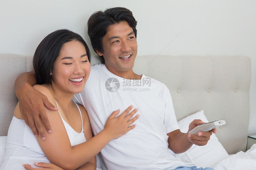 躺在床上看电视时笑着笑着的情侣房子公寓棉被羽绒被遥控微笑快乐男性睡衣电视图片