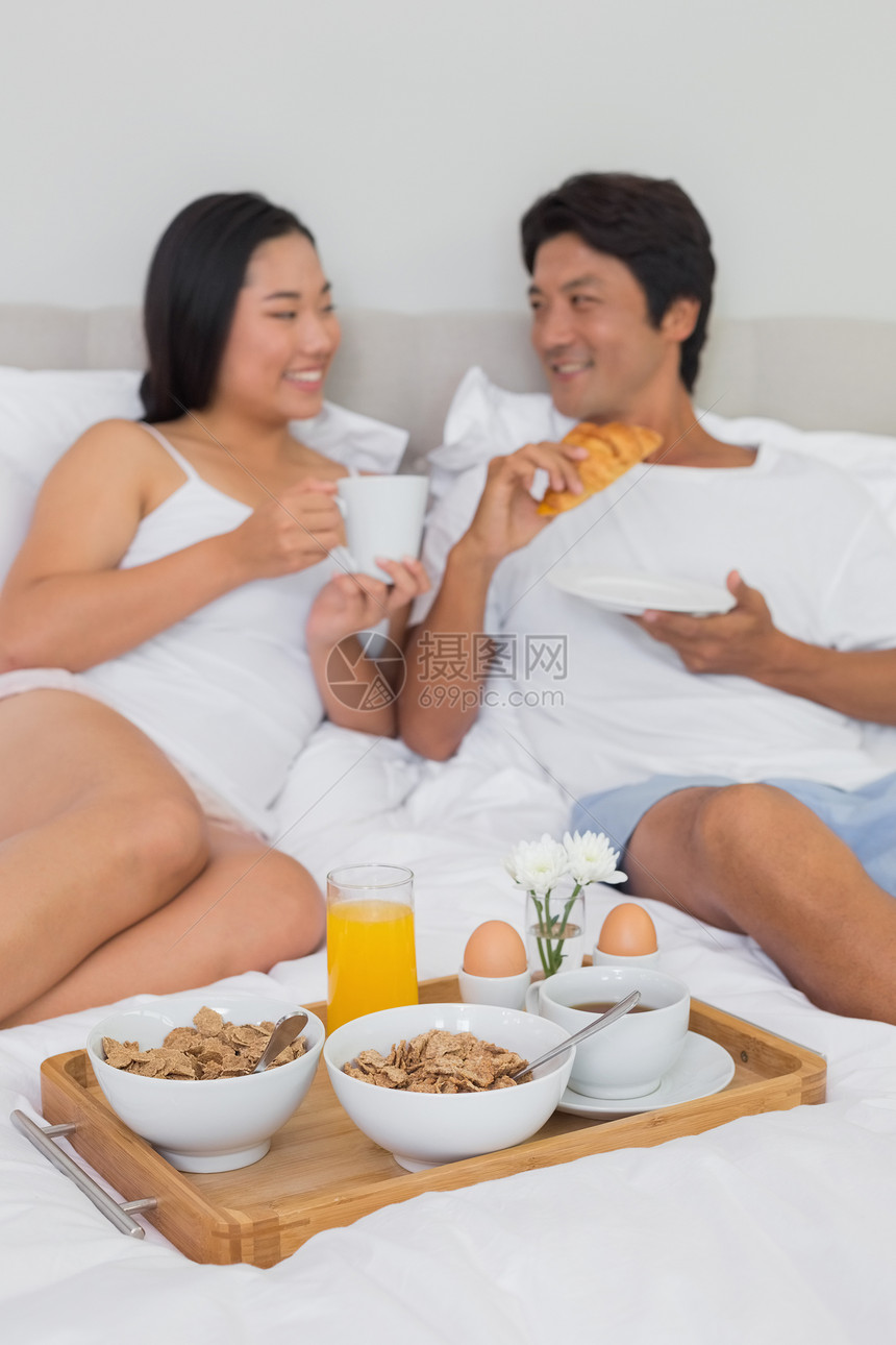 幸福的情侣在床上吃早餐卧室微笑咖啡橙汁面包休息睡衣家庭生活公寓被子图片