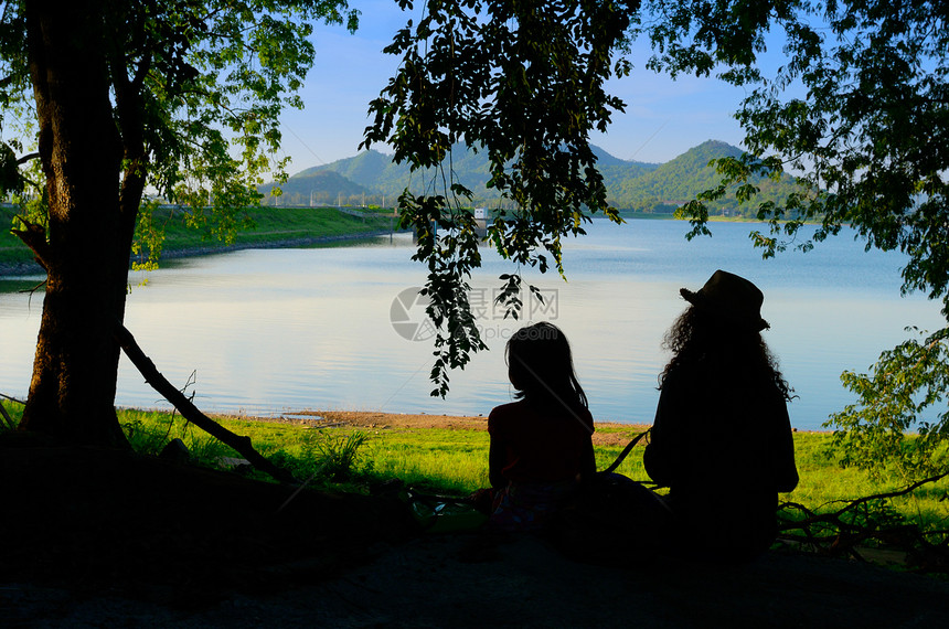两姐妹的休丽花坐在水库风景中放松图片