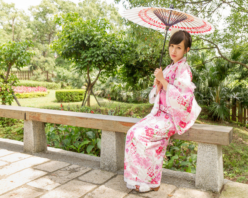 在日本风格的花园里 穿着浴袍的亚洲女人浴衣女士文化红色微笑和服女孩绿色裙子衣服图片
