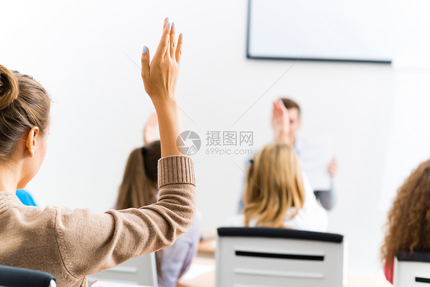 女性在班级中举起的手工作中学测验女士青少年成人教育家同学老师注意力图片