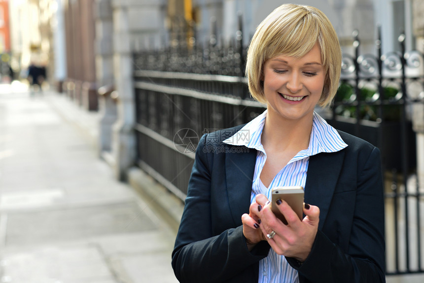 使用智能电话的女商务人士商务街道中年手机微笑经理消息人士讯息短信图片