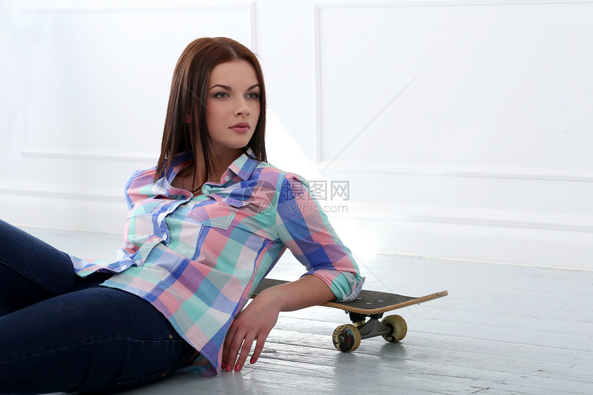 带滑板的漂亮女孩头发蓝色衣服女性地面女士工作室牛仔裤公寓房子图片