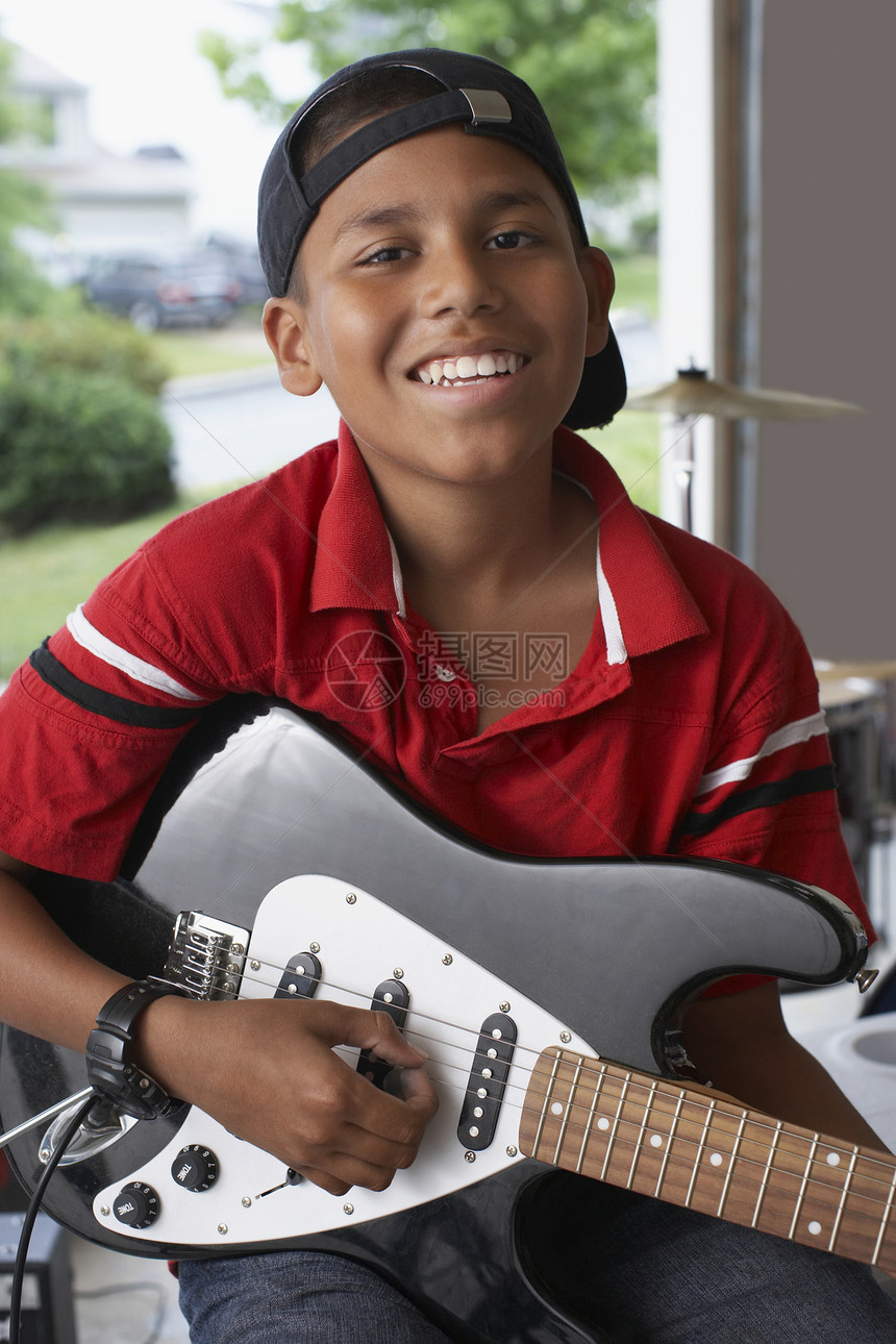 男(10-12)车库肖像上配有电吉他的男孩(10-12)图片