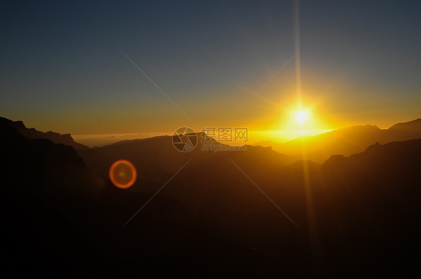 日落在山上黄色火山峡谷爬坡太阳橙子全景天空沙漠地平线图片