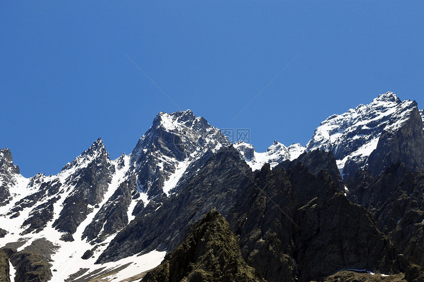 雪下和清蓝天空下的高加索山脉爬坡生长荒野季节滑冰旅游蓝色旅行冻结岩石图片