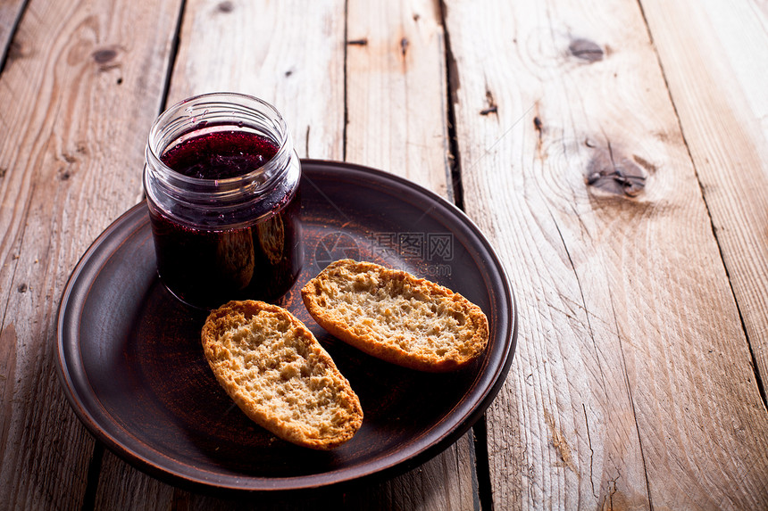 玻璃罐和饼干中的黑色黑卷曲心果酱果味木头季节陶瓷玻璃面包盘子棕色木板早餐图片