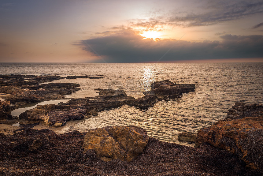 日落时落的洛基海滩反射场景海岸地平线海洋日落天空橙子岩石海浪图片