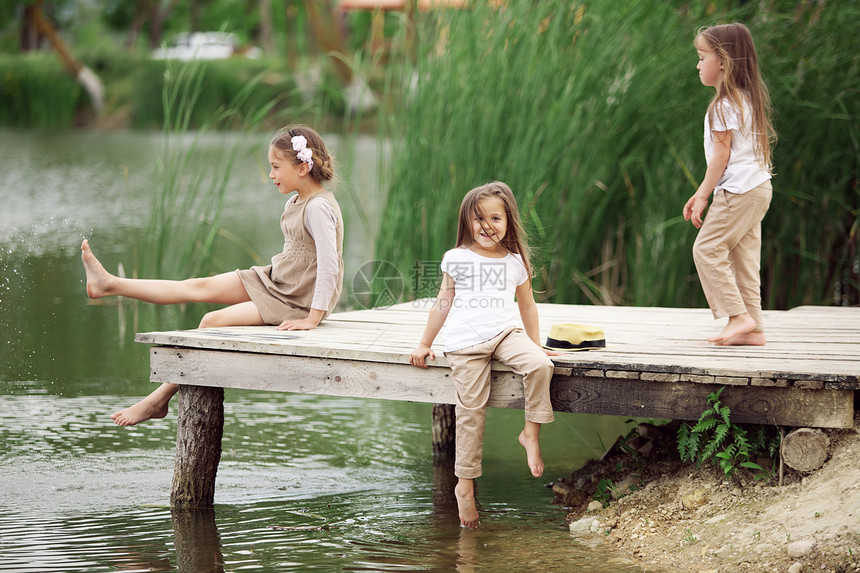 池塘附近儿童家庭娱乐女孩们姐妹乡村女儿们空闲乐趣友谊泊位图片