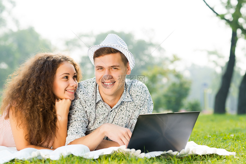 一对夫妇一起躺在公园里 带着笔记本电脑喜悦技术夫妻幸福网络男人朋友们闲暇友谊女孩图片