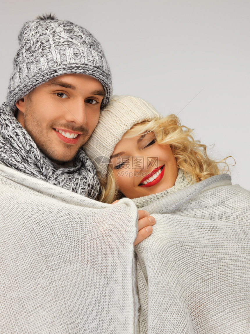 在温暖的毯子下的家庭夫妇快乐微笑季节围巾帽子女孩领带家庭女士套衫图片