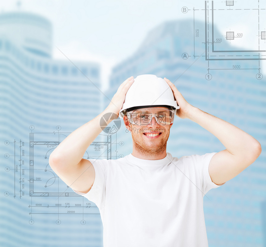 戴着安全眼镜的白头盔男建筑师摩天大楼风镜微笑安全城市方案承包商绘画技术员蓝图图片