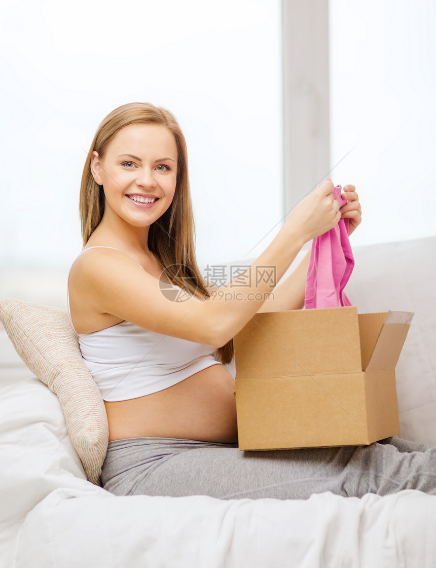 微笑着的孕妇打开包裹箱服务命令开襟衫幸福父母女性女孩展示新生肚子图片