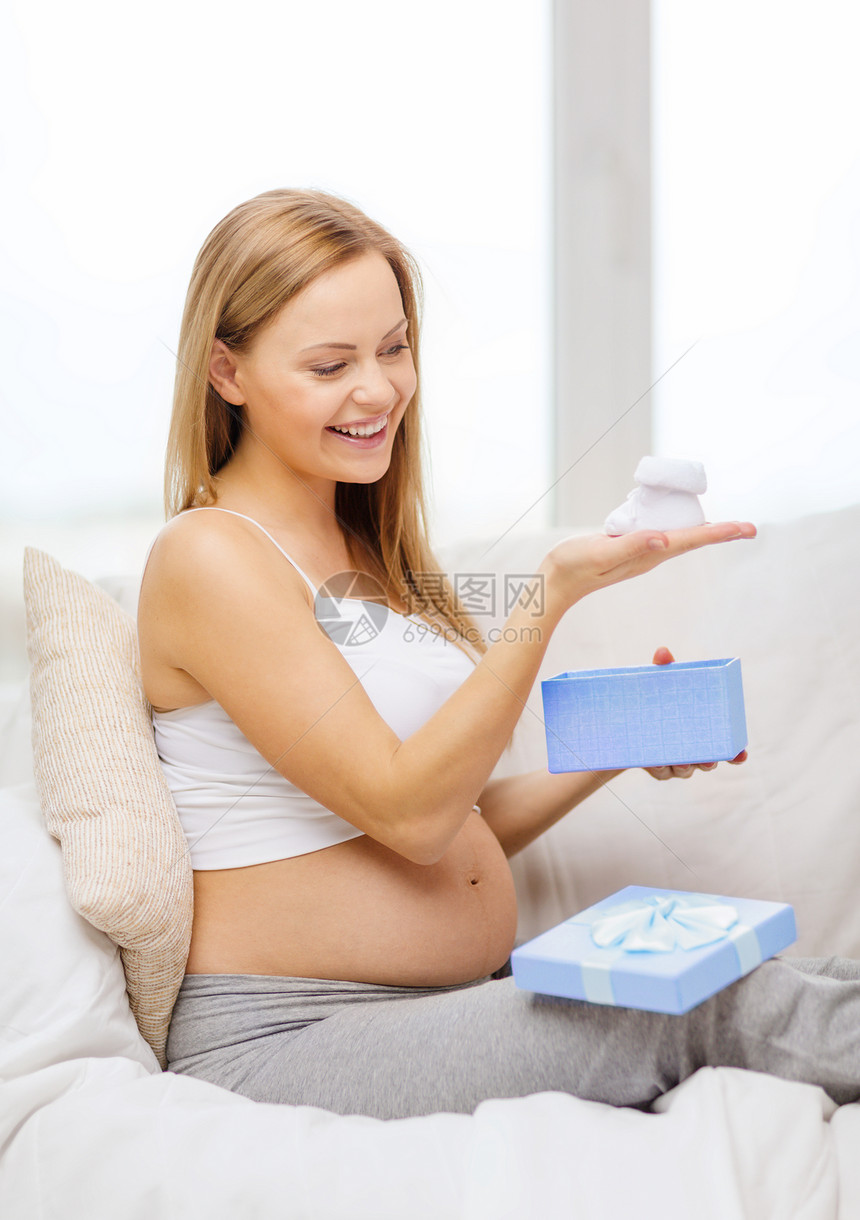 带礼物盒和受款人 微笑着的孕妇礼物父母蓝色母亲快乐婴儿沙发腹部幸福惊喜图片