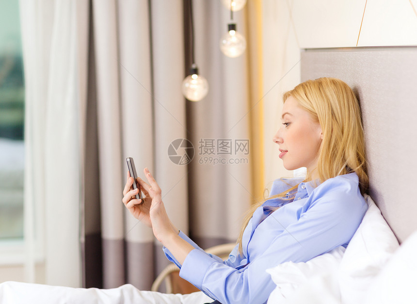 在酒店房间有智能手机的快乐女商务人士互联网女士休息老板技术电子邮件检查旅行电话微笑图片