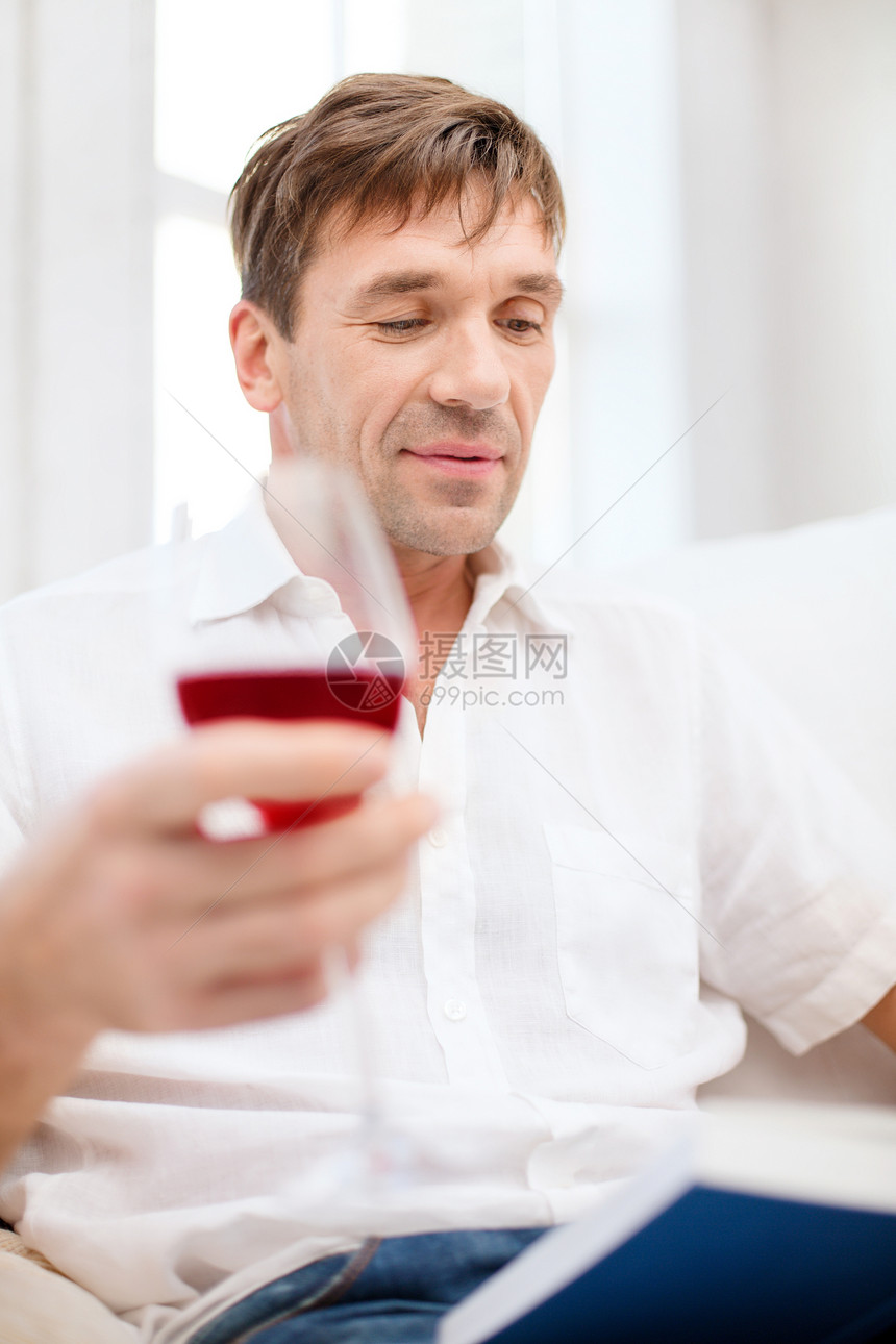 男人在家里对书和红酒喝得开心图片