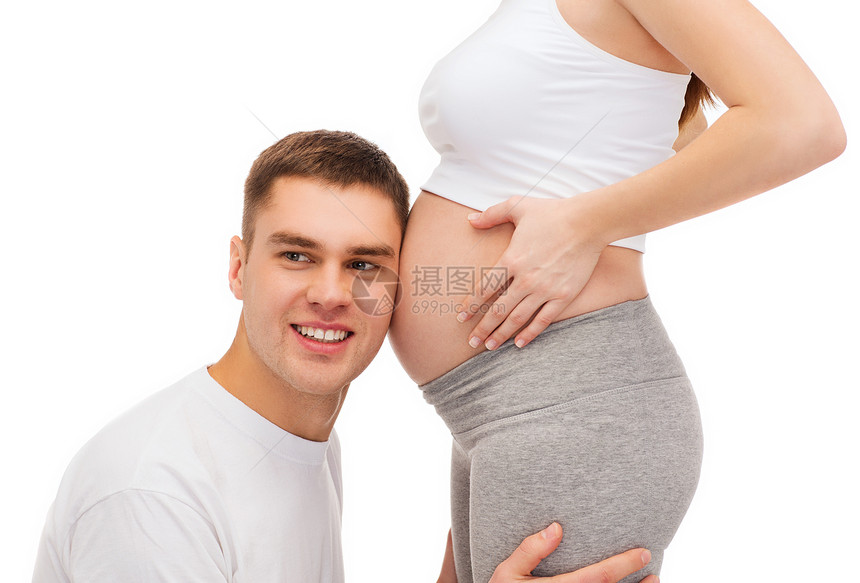 快乐的父亲听着他怀孕妻子的肚子母性婴儿男性微笑产妇女士男人孩子父母爸爸图片