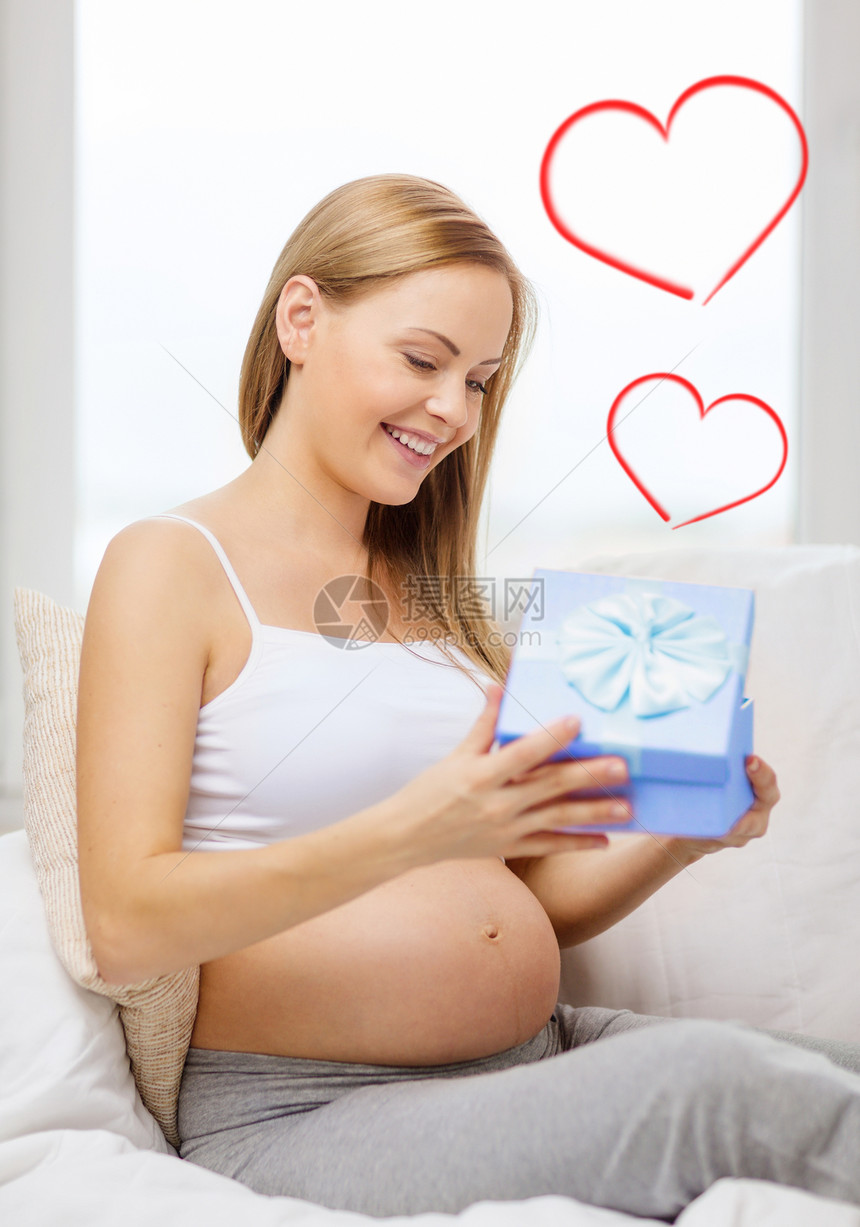 开启礼物盒的孕妇笑着微笑父母盒子沙发肚子展示蓝色母亲婴儿妈妈们母性图片
