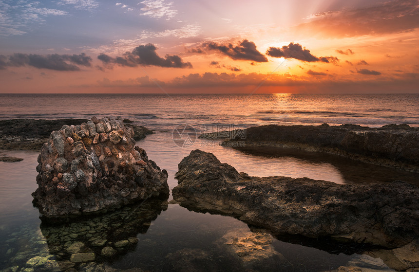 太阳用古老的废墟日落在海和洛基海岸上空橙子光束岩石射线风景反射天空旅行海浪阳光图片