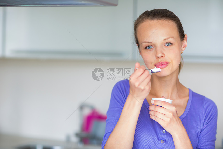 快乐的年轻女子在厨房吃酸奶牛奶奶制品青春女性营养青年女士微笑小吃食物图片