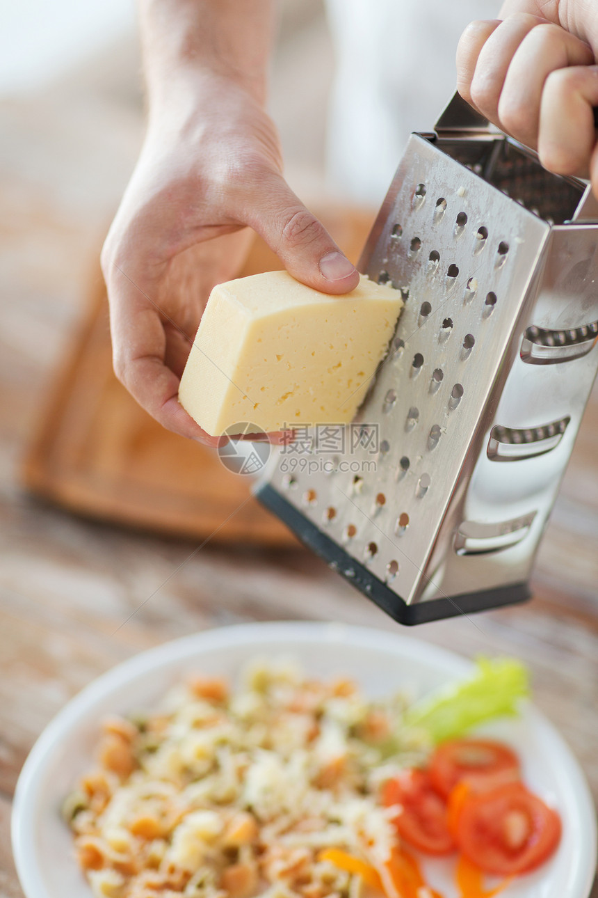 紧紧的男性手 在意大利面上磨奶酪工具围裙桌子奶制品食物盘子木板蔬菜男人沙拉图片