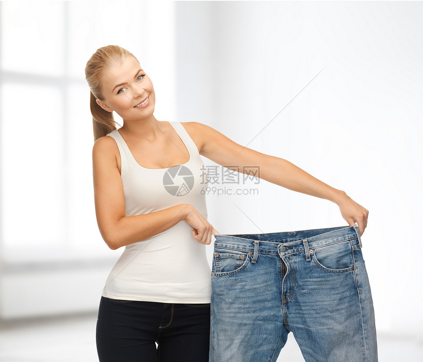 穿着大裤子的运动妇女腰围福利测量损失女性衣服燃烧房间饮食微笑图片