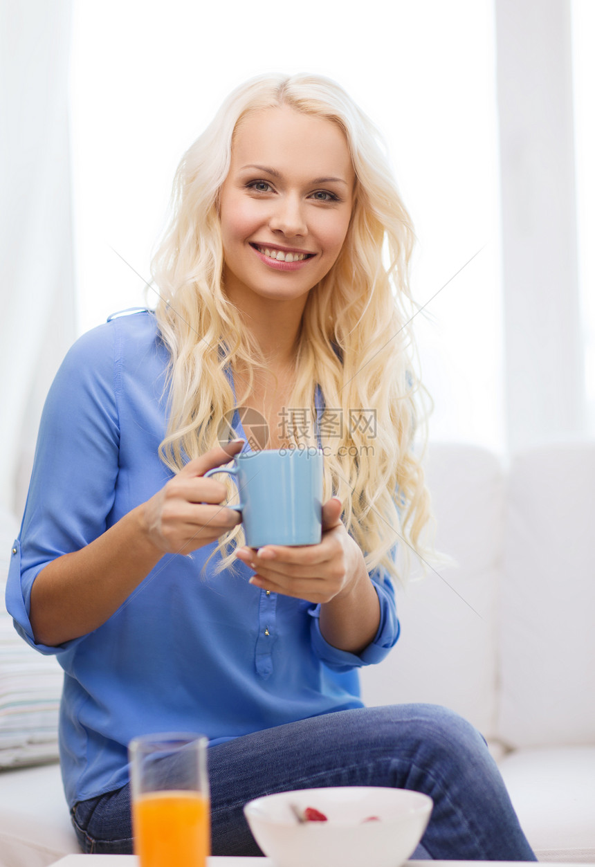 带着一杯茶的笑着女人 吃早餐玻璃杯子饮料谷物橙子女性咖啡成人沙发果汁图片
