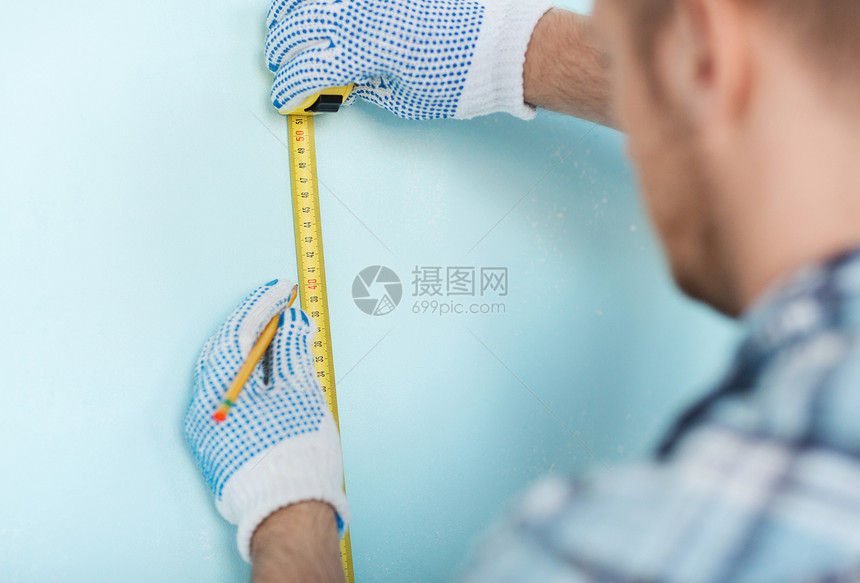 戴上手套用胶带测量墙壁的男性维修开发商改造工程男人工作安装承包商建设者房子图片