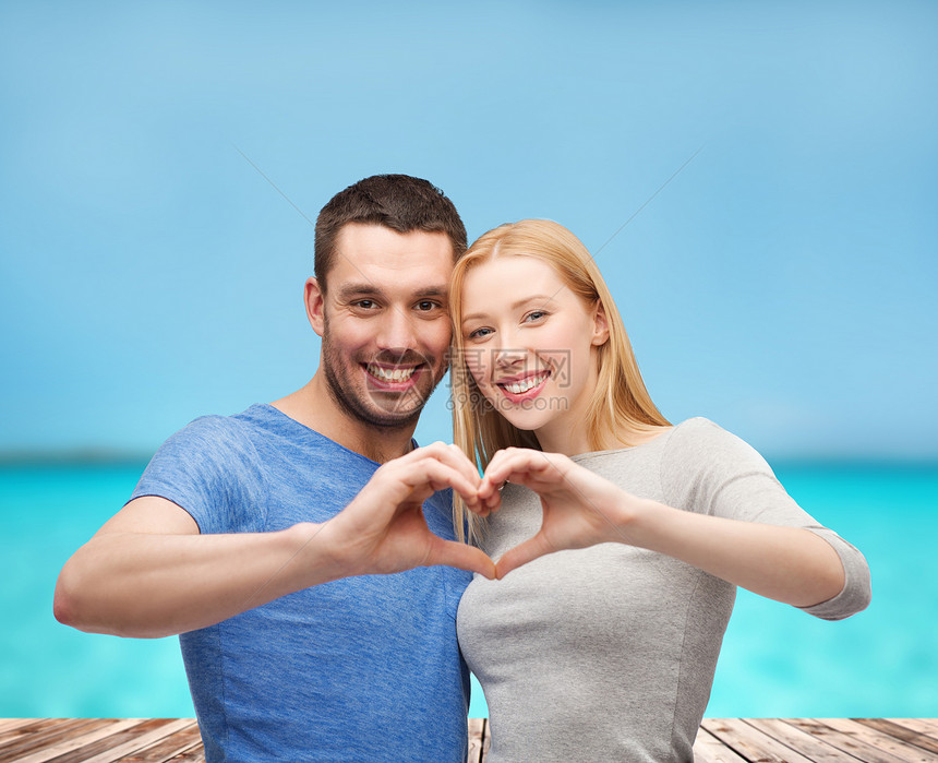 微笑的情侣用双手露出心泊位幸福女士男人恋爱海洋家庭木头亲热男生图片