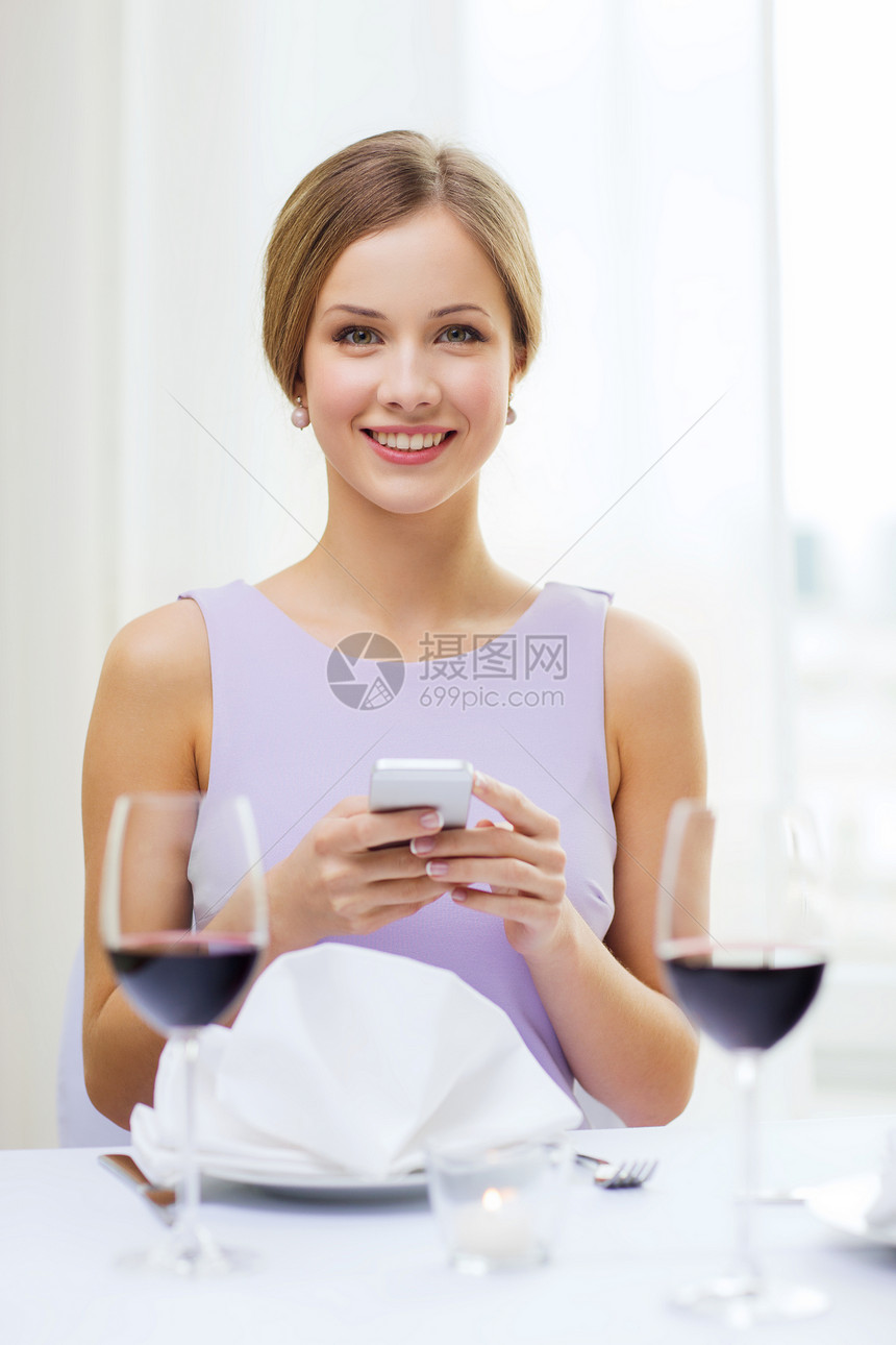 以智能手机微笑的女子裙子饮料上网幸福酒精蜡烛成人餐厅技术周年图片