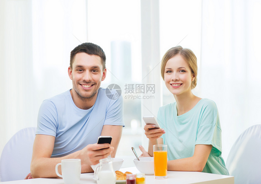 带着智能手机微笑的情侣阅读新闻早餐羊角家庭电话妻子上网牛奶成人谷物男朋友图片