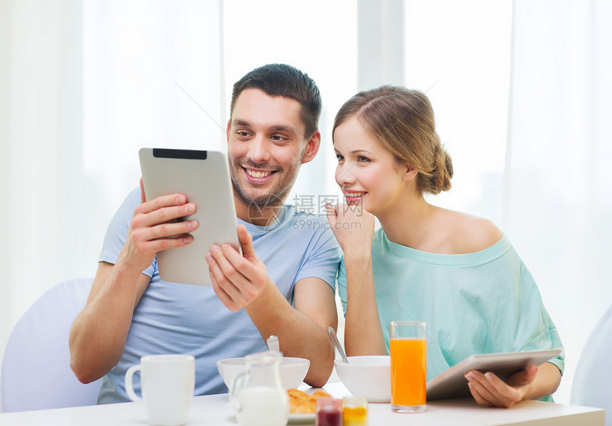 微笑的情侣与平板电脑Pc阅读新闻互联网羊角厨房早餐女朋友男朋友咖啡杯子谷物成人图片