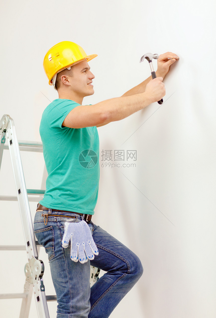男人在头盔中微笑 在墙上钉钉钉锤子建筑学指甲承包商公寓工程师开发商男性工人工程图片