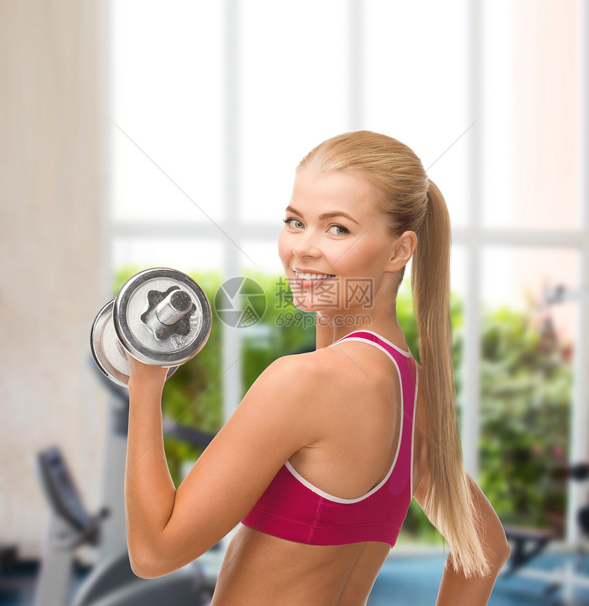 带着重钢的哑巴微笑的女人中心光盘手臂重量健身房训练减肥肌肉运动装女孩图片